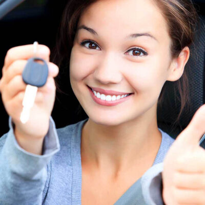 happy women smiling in car with thumbs up and car keys